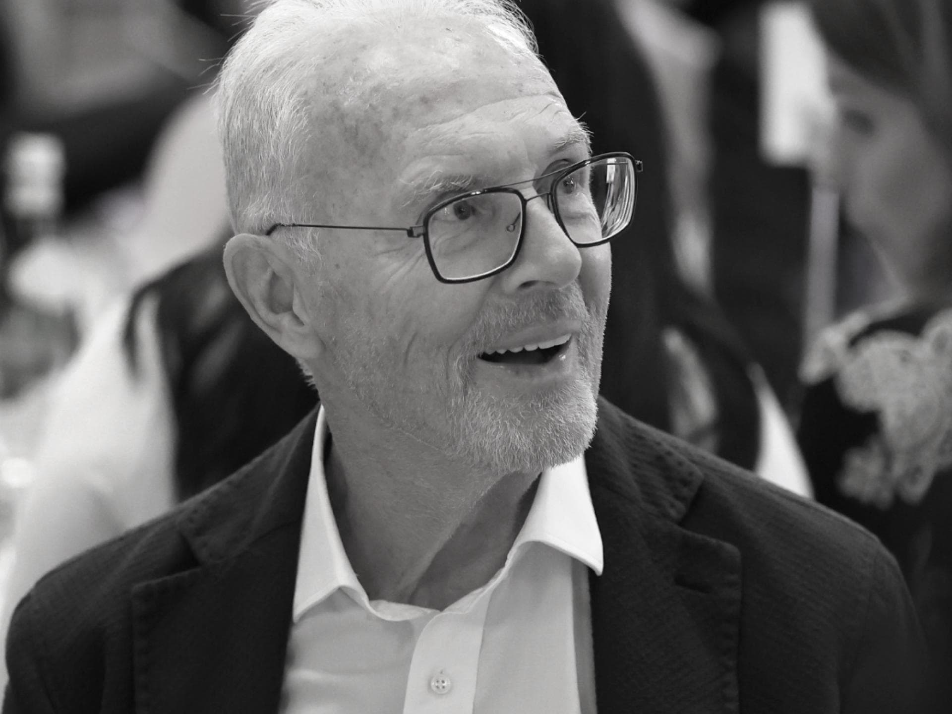 Franz Beckenbauer schaut lächelnd mit Brille zur Seite
