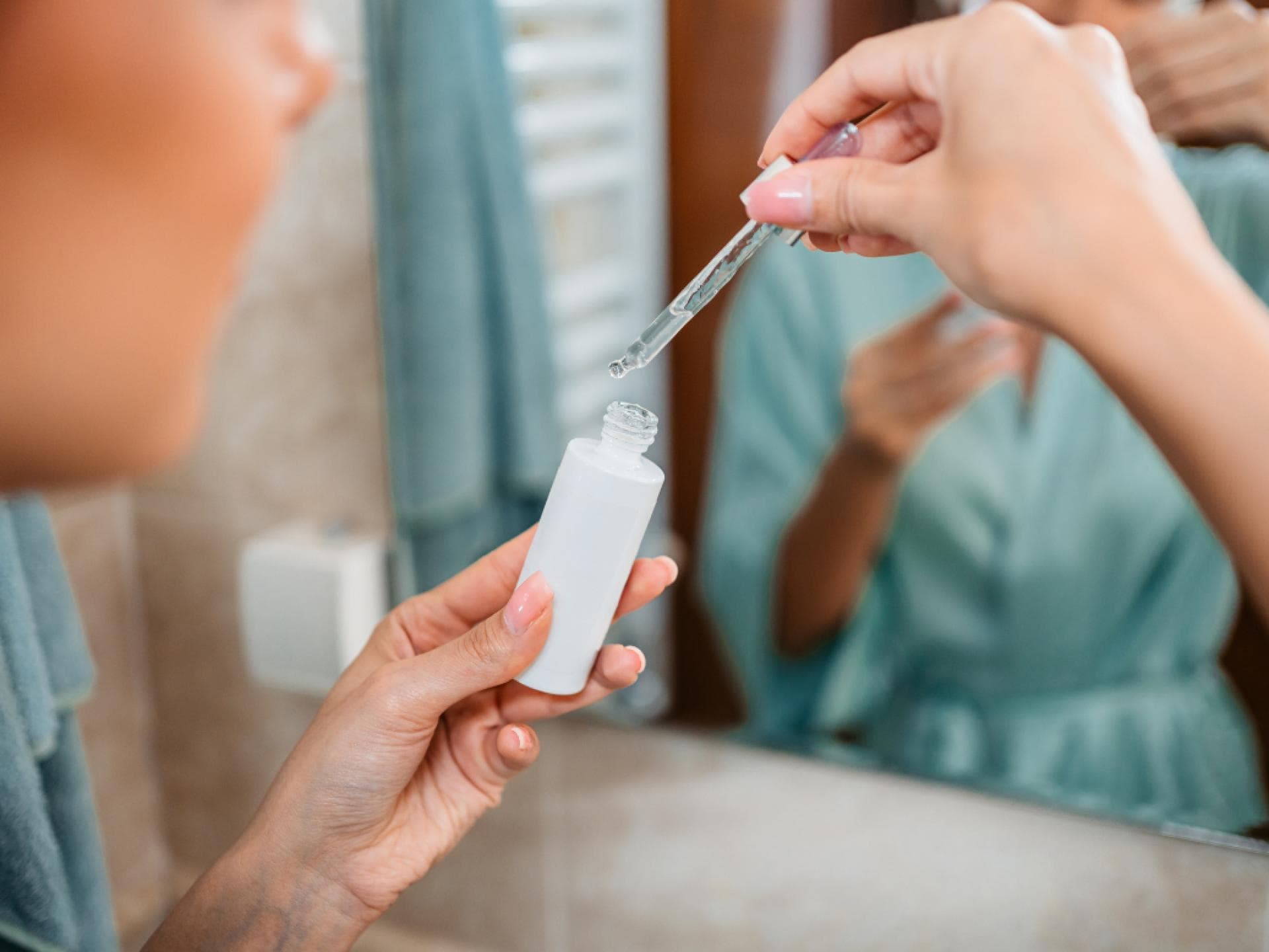 Kurkuma-Öl für Anti-Aging Frau mit Pipette vor Spiegel