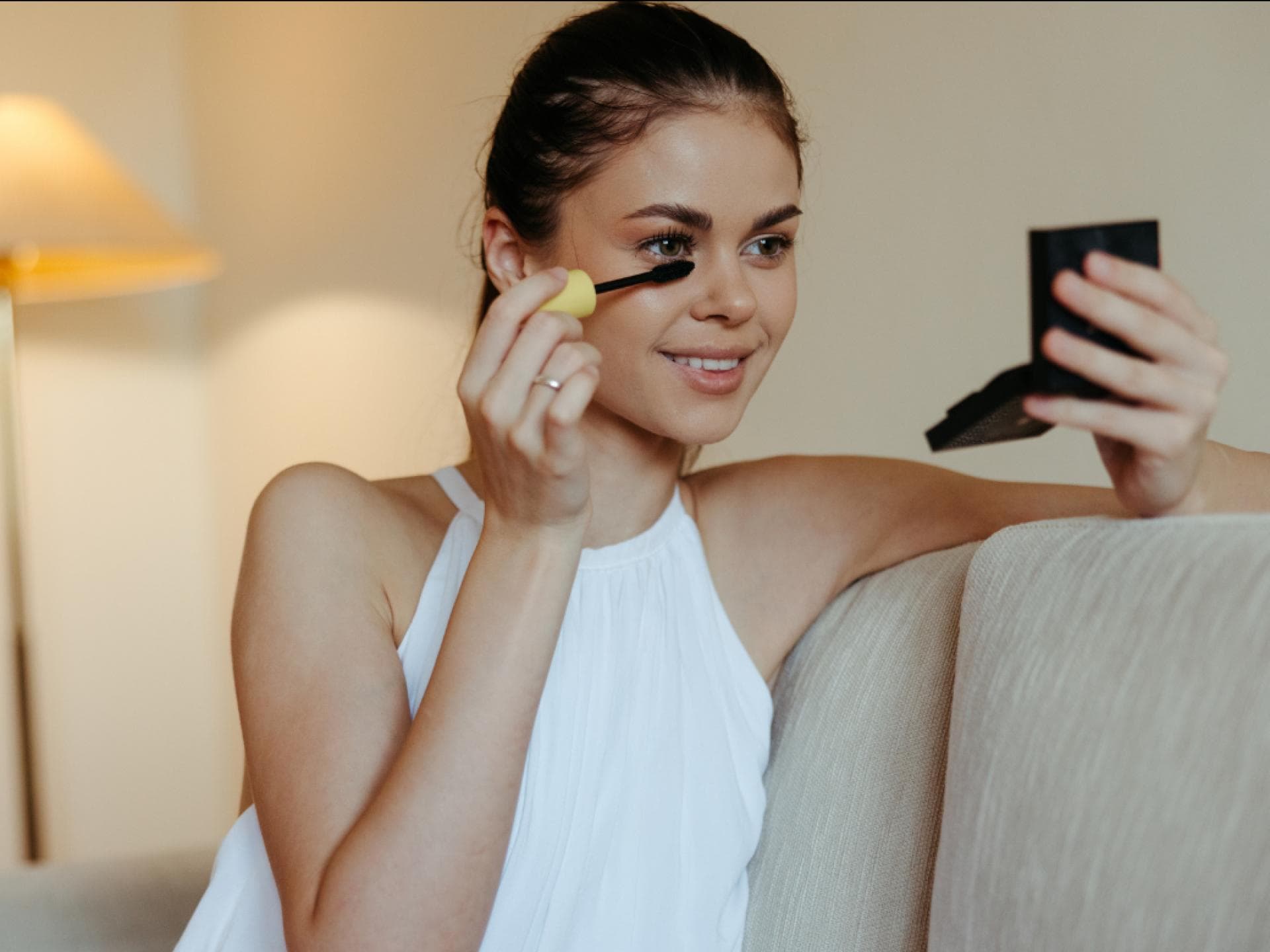 Mascara für Lifting und Schwung Frau tuscht Wimpern vor Handspiegel