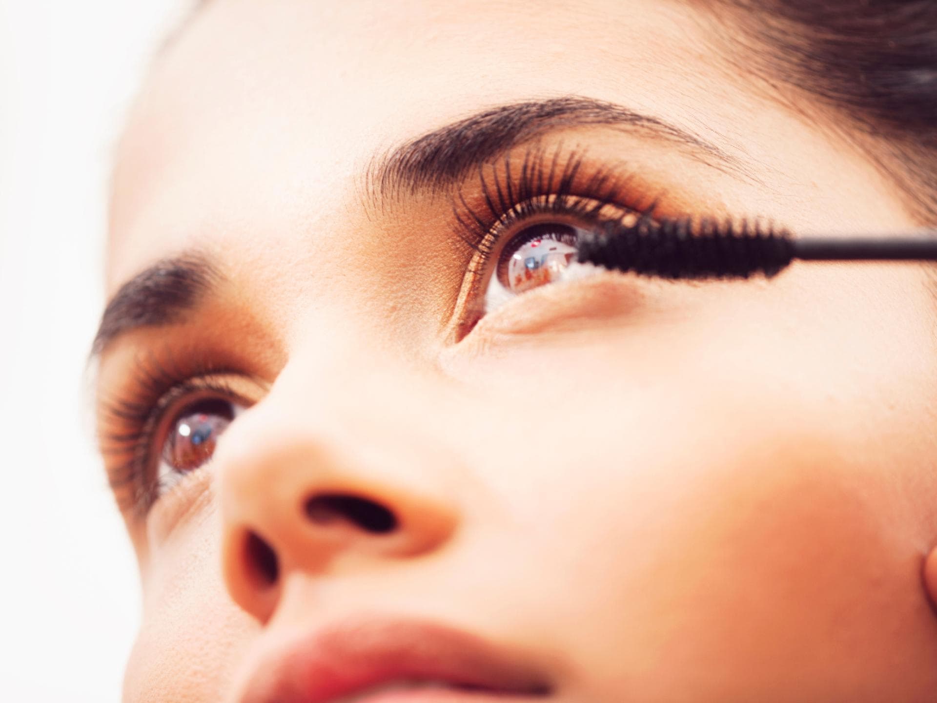 Mascara mit Peptiden Frau schaut nach oben und trägt Mascara auf