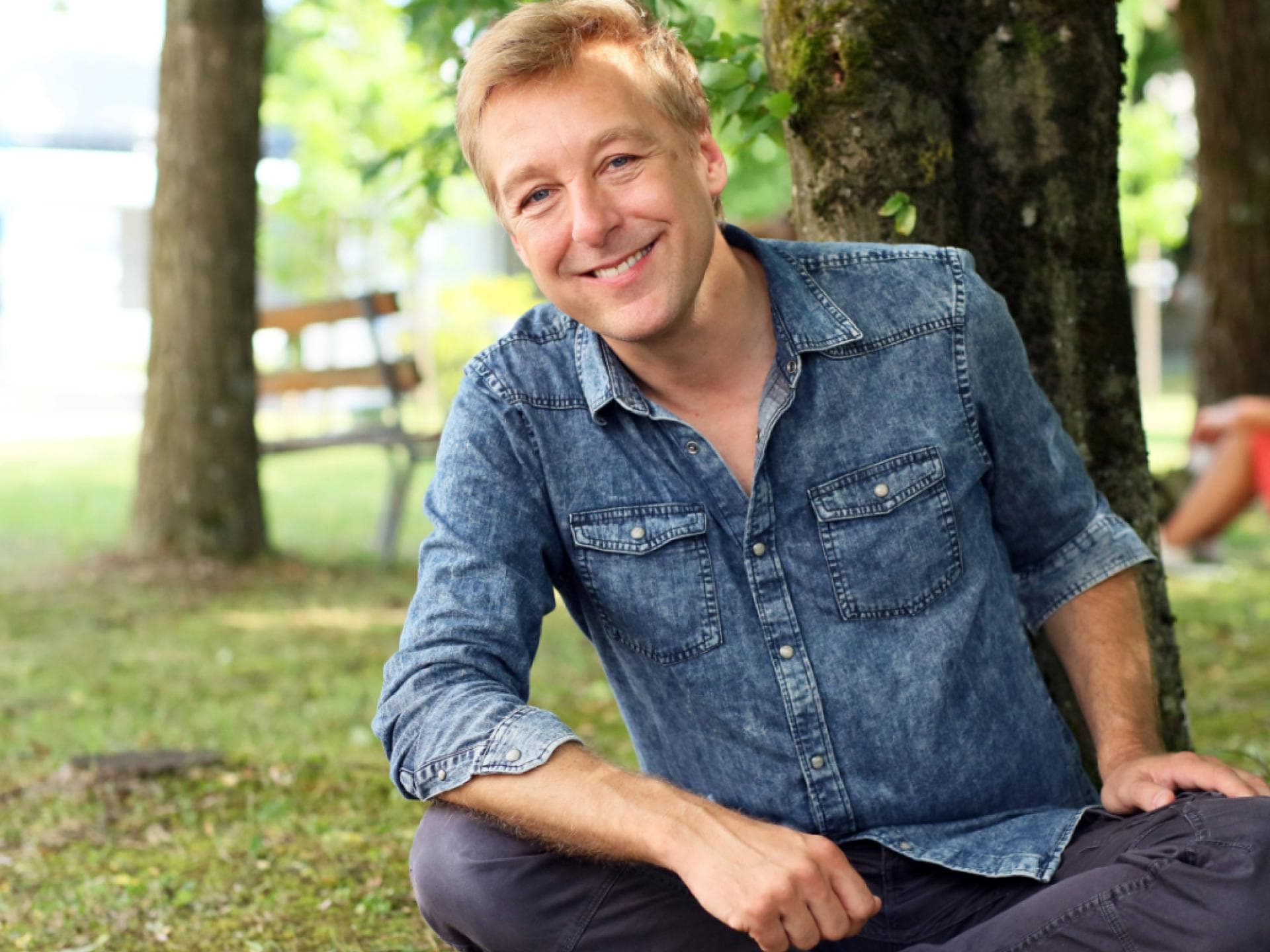 Max Müller sitzt lächelnd auf Stein im Park