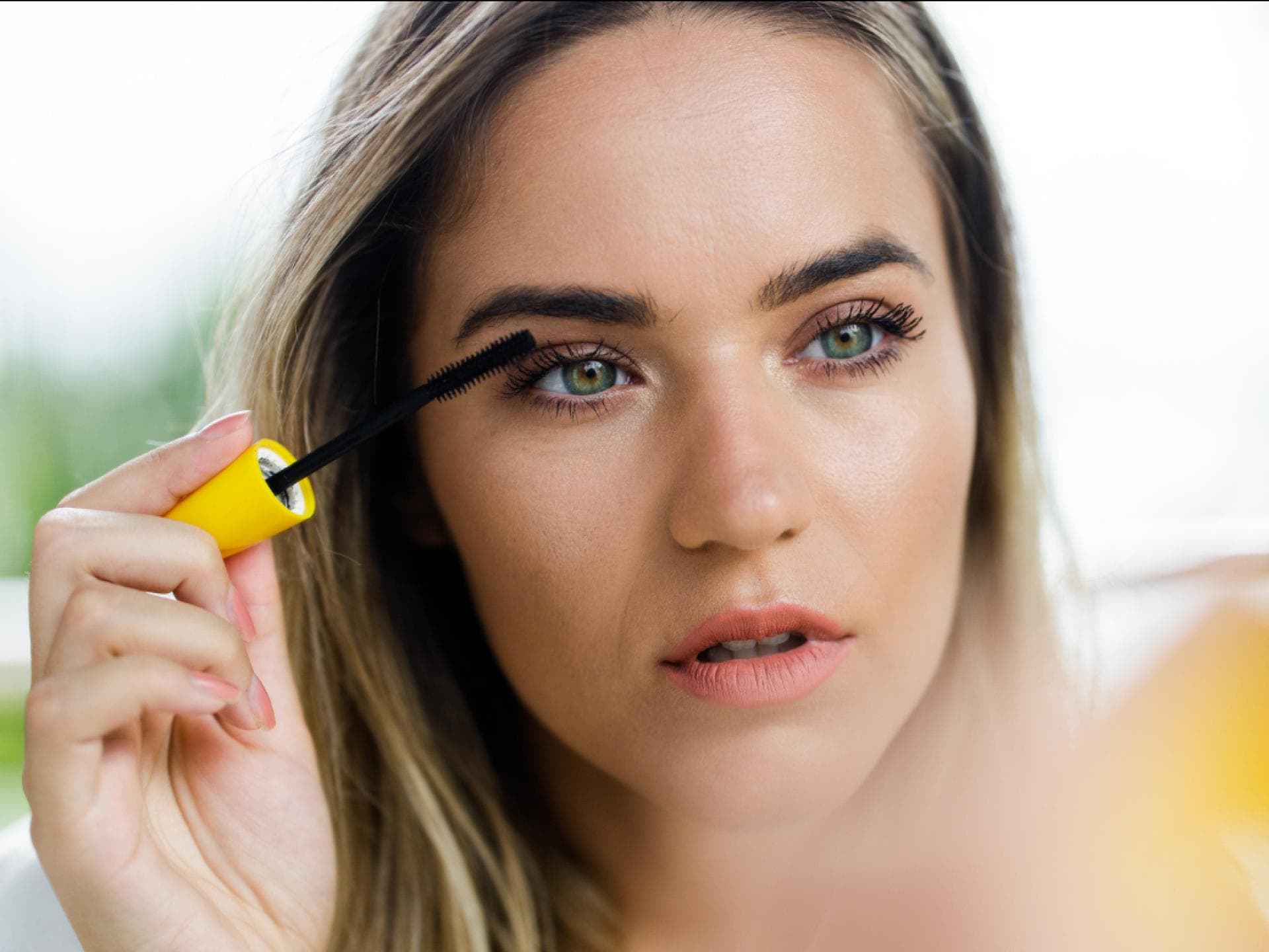 Volumen-Mascara bei Rossmann Frau trägt Mascara vor Spiegel auf