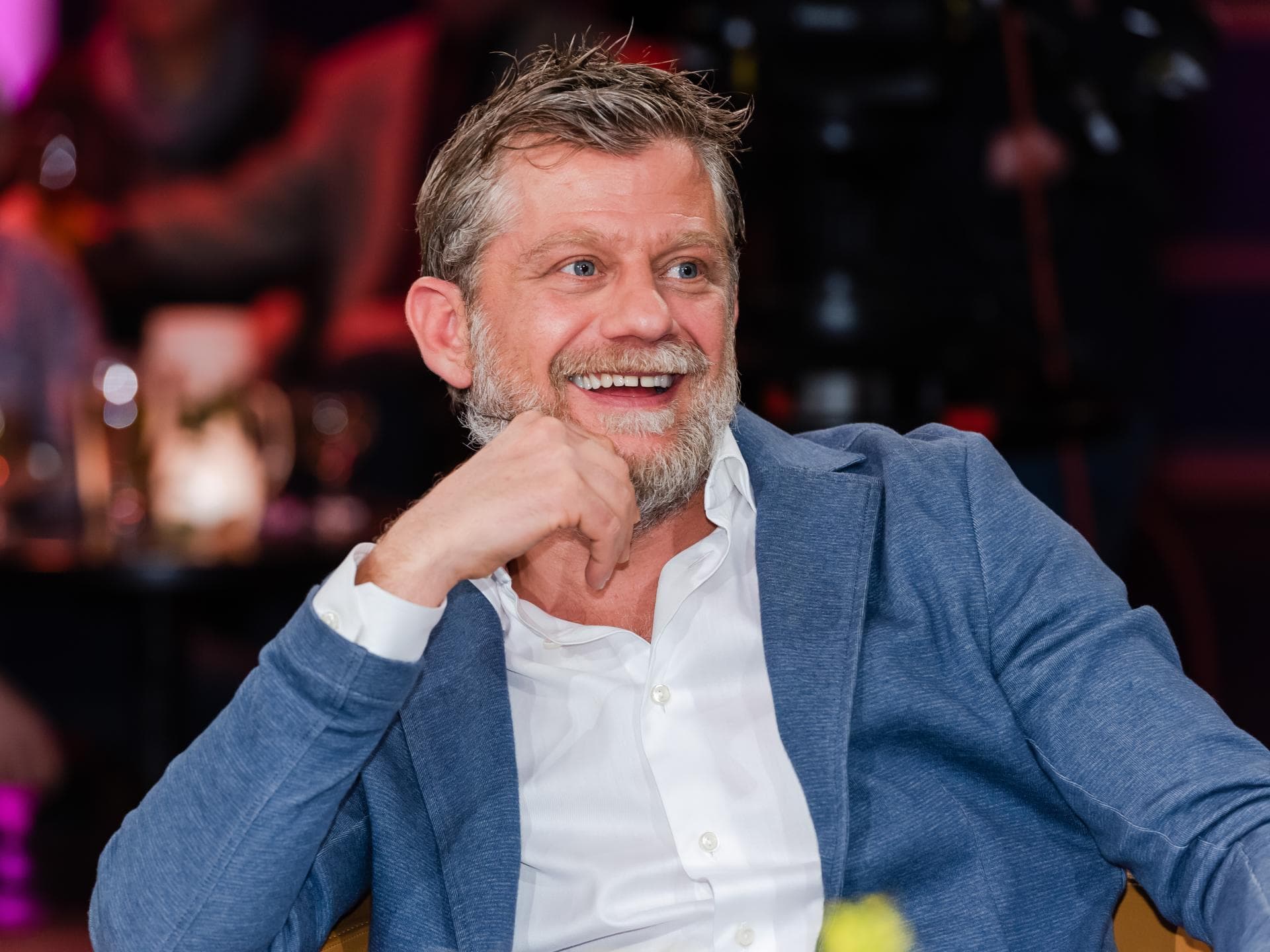 Andreas Guenther guckt lachend zur Seite, Hand am Kinn
