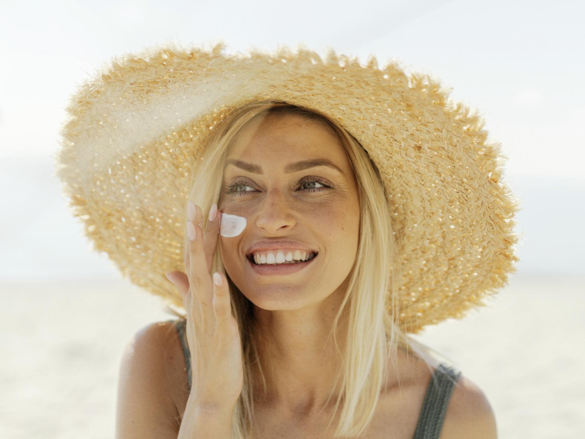 Blondine trägt Sonnenschutz auf