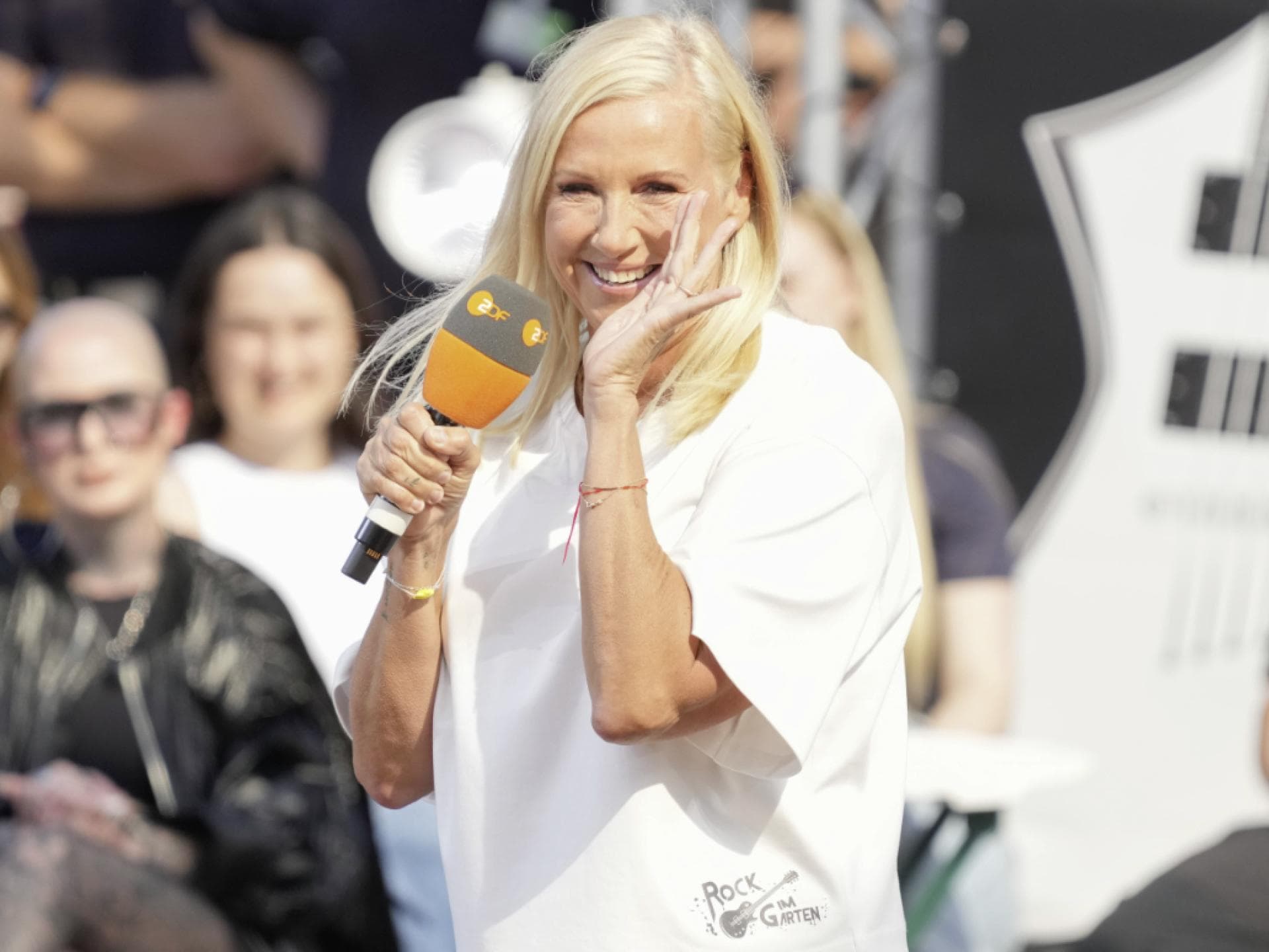 Andrea Kiewel lacht mit Hand am Mund