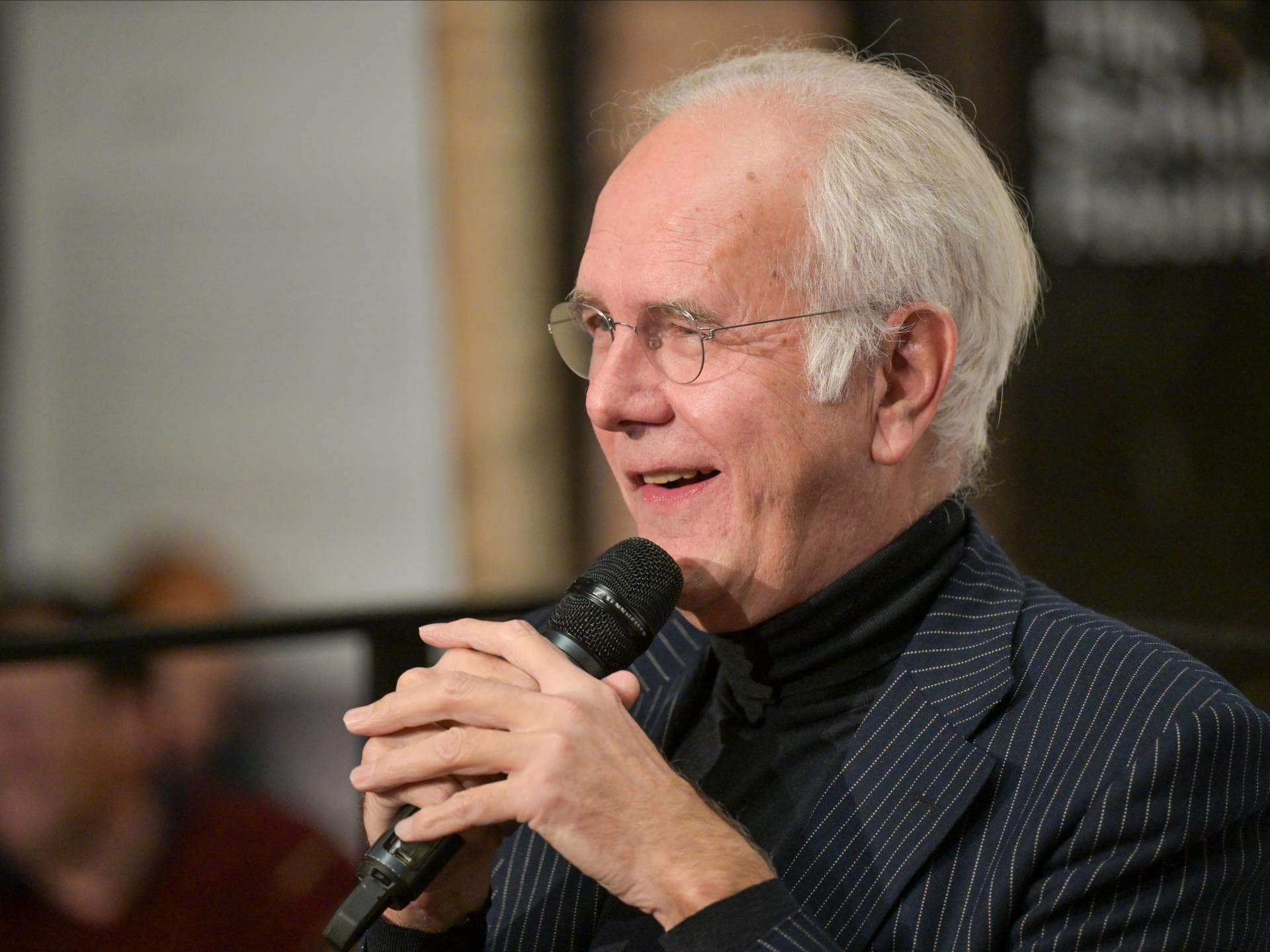 Harald Schmidt von der Seite mit einem Mikrofon in der Hand