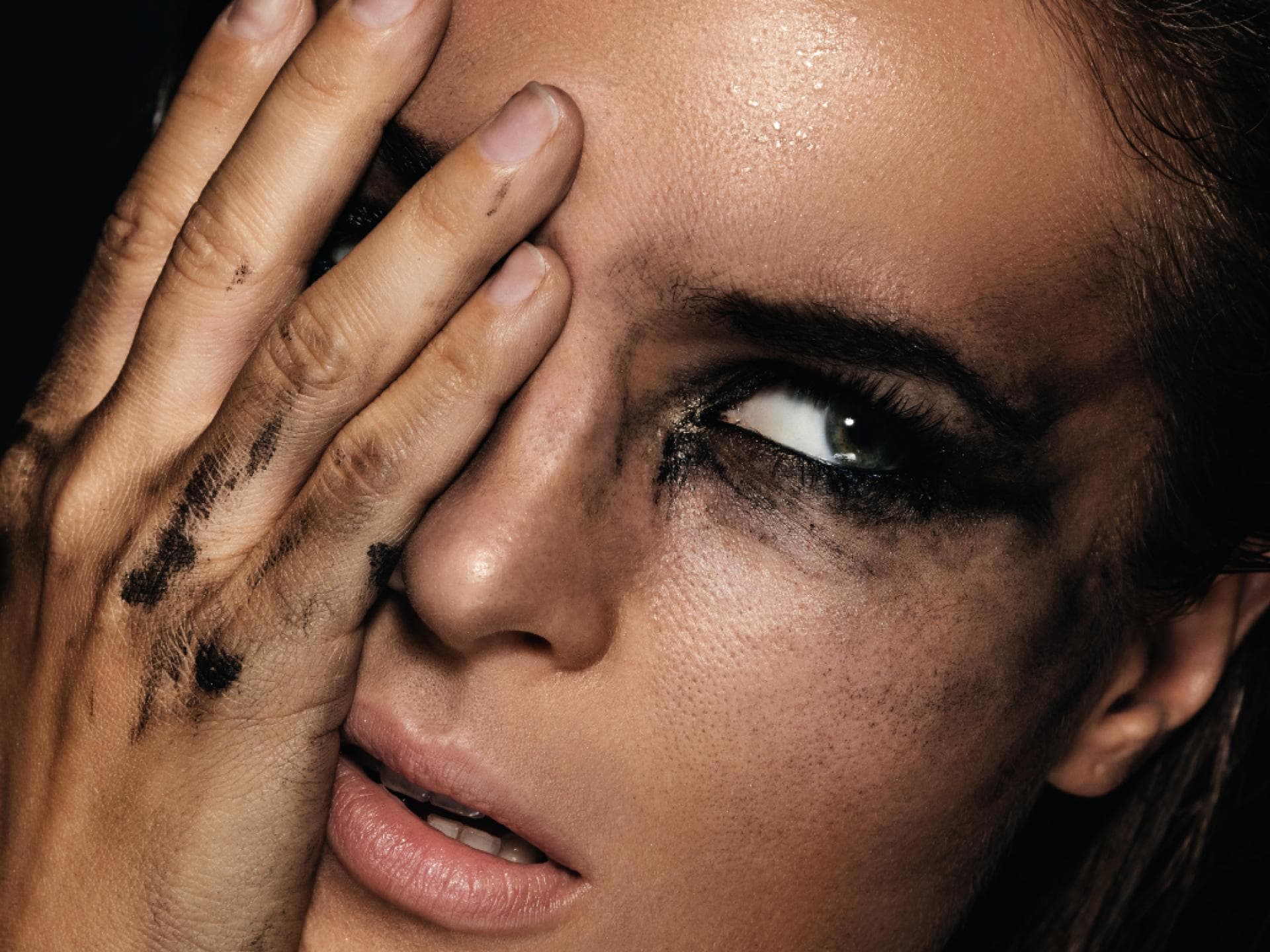 Frau hält Auge zu und hat verschmierte Mascara