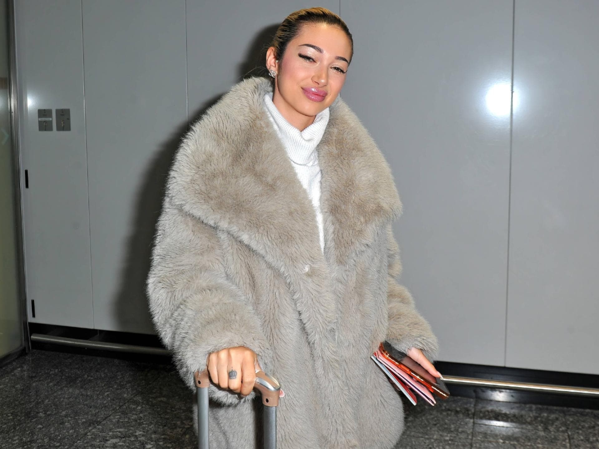Ariel im Fake-Fur-Mantel am Flughafen