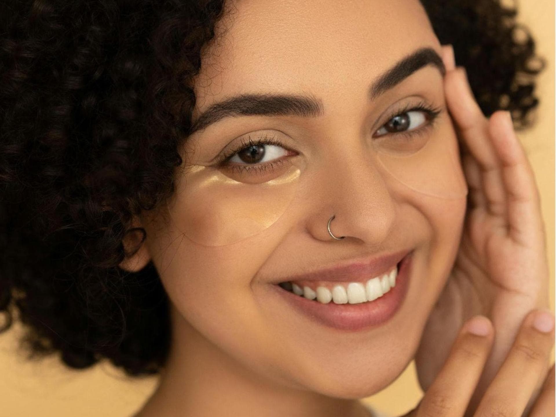 Eine Frau strahlt mit Augenpads in die Kamera