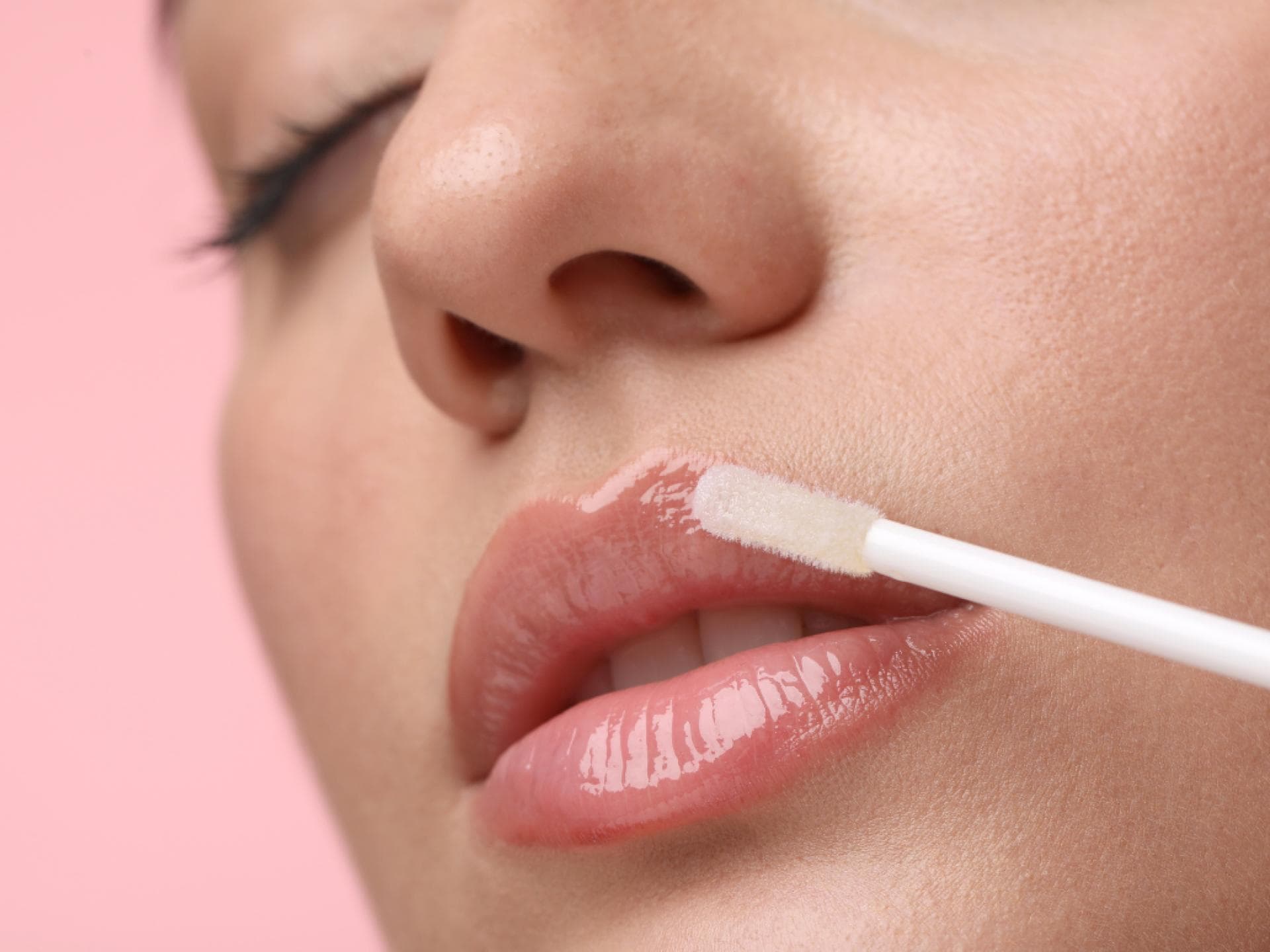 Frau mit vollen Lippen trägt Lipgloss auf