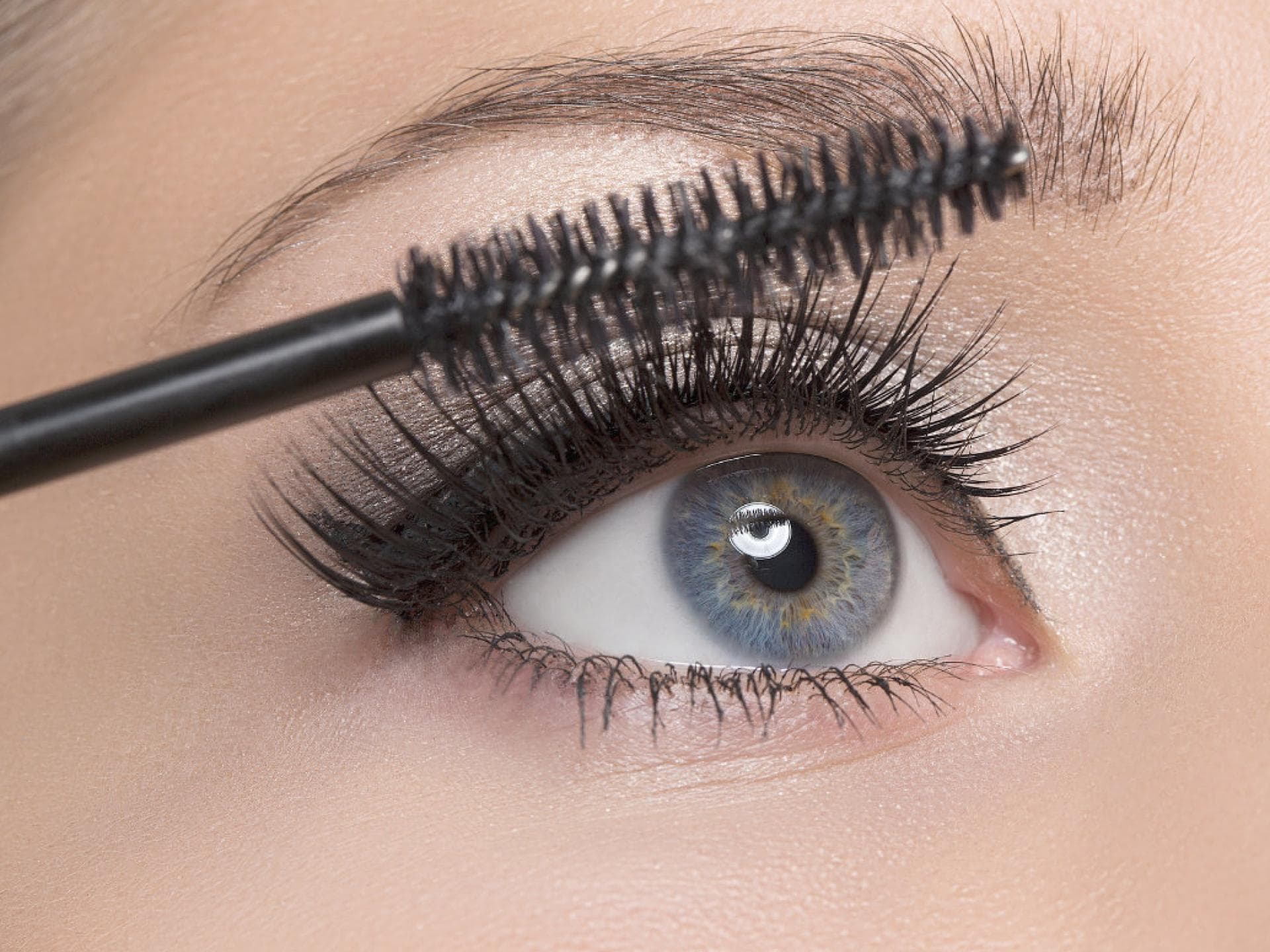 Frau mit blauen Augen benutzt Mascara