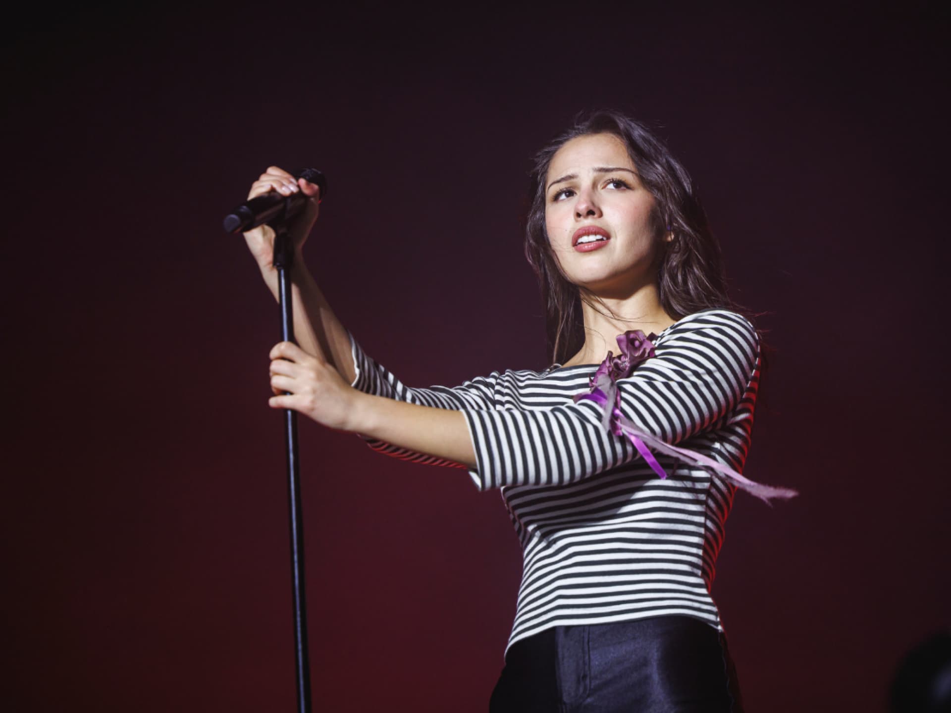 Olivia Rodrigo mit Mikrofon und traurigem Blick