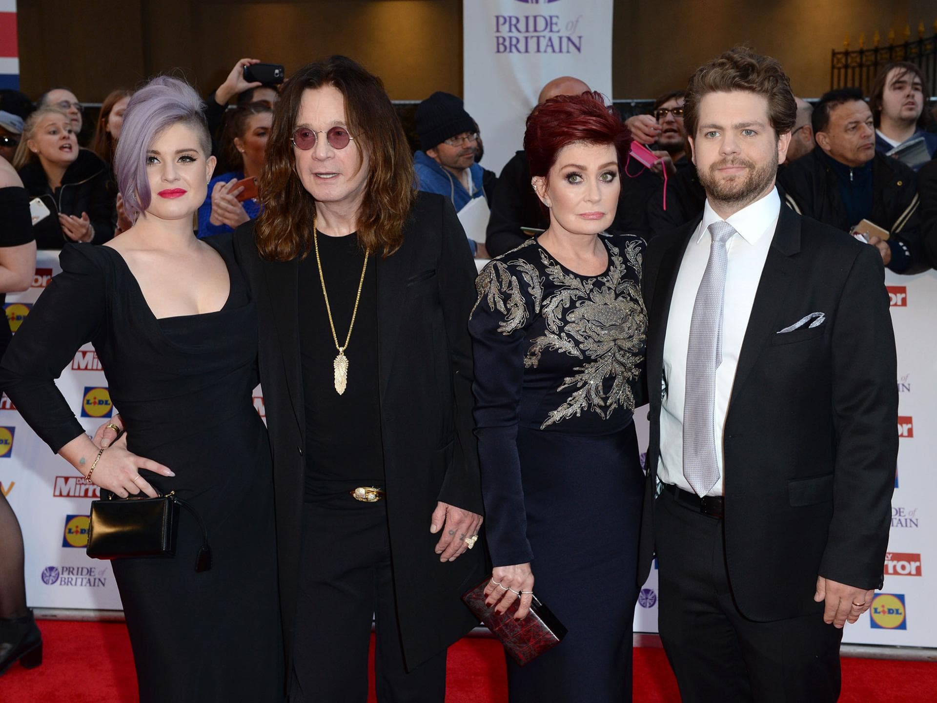 Kelly, Ozzy, Sharon und Jack Osbourne nebeneinander, Menschen im Hintergrund