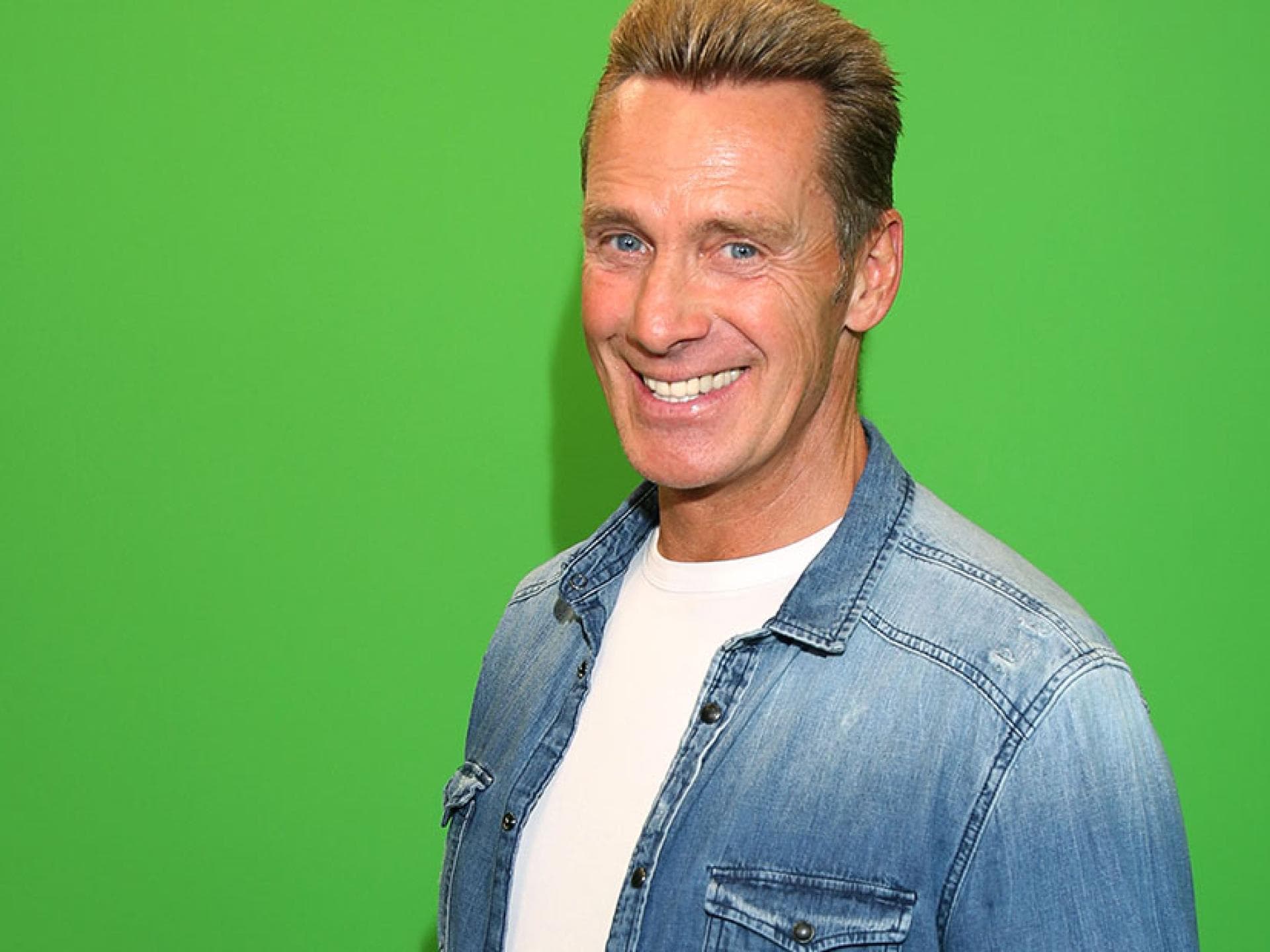Jürgen Milski strahlt vor einer grünen Wand