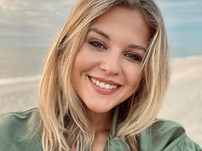 Josefin Bressel lächelt in ihr Handy am Strand.