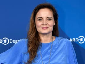 Elisabeth Lanz posiert im blauen Oberteil vor blauer Wand