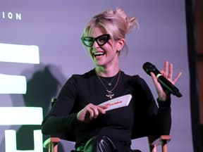 Kelly Osbourne lacht mit Brille und Mikrofon in der Hand