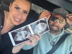 Virginia Weiß und Ehemann Andrew lächeln und zeigen ein Ultraschallbild
