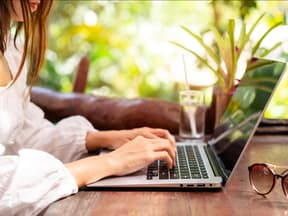 Junge Frau arbeitet im Urlaub am Laptop 