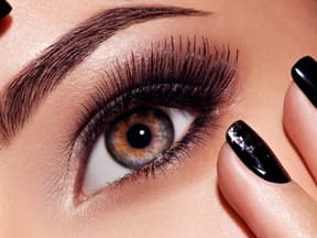 Frau mit langen Wimpern und schwarzen Nägeln
