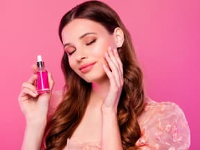 Frau mit Serum vor pinkem Hintergrund