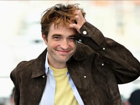 Robert Pattinson lächelt mit zerzausten Haaren