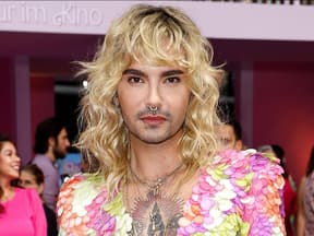 Bill Kaulitz mit blonden locken vor pinker wand