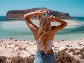 Frau mit langen Haaren blickt aufs Meer
