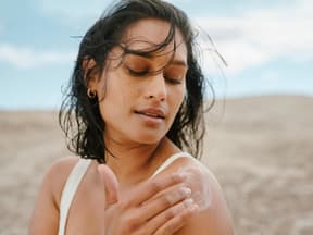 Frau am Strand cremt sich ein