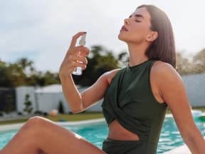 Frau sonnt sich am Pool mit Bodyspray