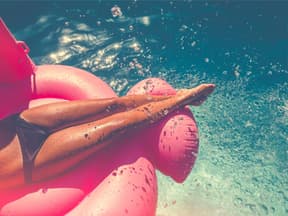 Eine Frau liegt auf einer Luftmatratze im Pool