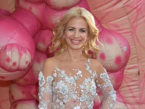 Susan Sideropoulos im weißen Glamour-Kleid, pinker Hintergrund