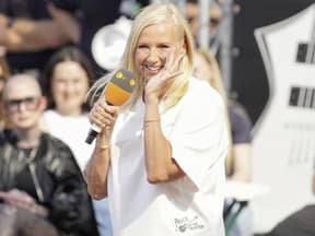 Andrea Kiewel lacht mit Hand am Mund
