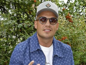 Pietro Lombardi lächelt mit Sonnenbrille vor grünen Büschen