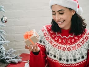 Eine Frau schaut strahlend ein Geschenk an