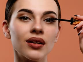 Frau mit Abend-Make-up trägt Mascara auf