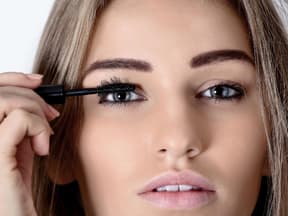 Frau mit langen Wimpern trägt Mascara auf