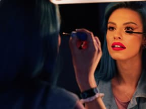 Frau tuscht Mascara vor Spiegel auf