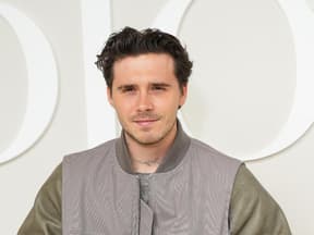 Brooklyn Beckham lächelt leicht, heller Hintergrund