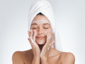 Frau reinigt ihr Gesicht, Schaum im Gesicht