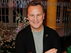 Guido Maria Kretschmer lächelt vor Blumen-Bouquet