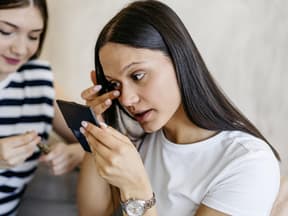 Frau entfernt Mascara-Reste unter dem Auge