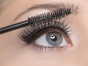 Frau mit blauen Augen benutzt Mascara