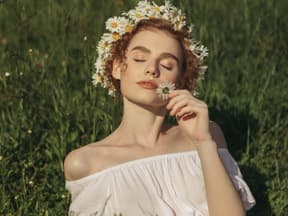 Frau mit Blumenkranz auf grüner Wiese