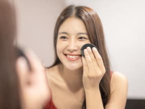 Frau trägt Make-up mit Cushion auf