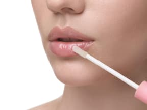 Frau trägt Lippenöl auf
