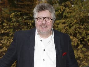 Michael Schanze im Anzug, Busch im Hintergrund
