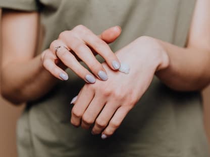 Frau cremt Hand ein