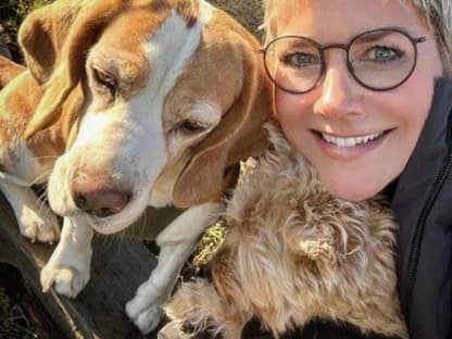 Inka Bause lächelt in die Kamera mit zwei Hunden