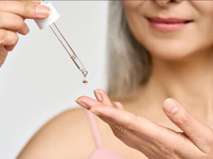 Anti-Aging-Serum Menopause Frau mit Pipette gibt Anti-Aging-Serum auf Finger